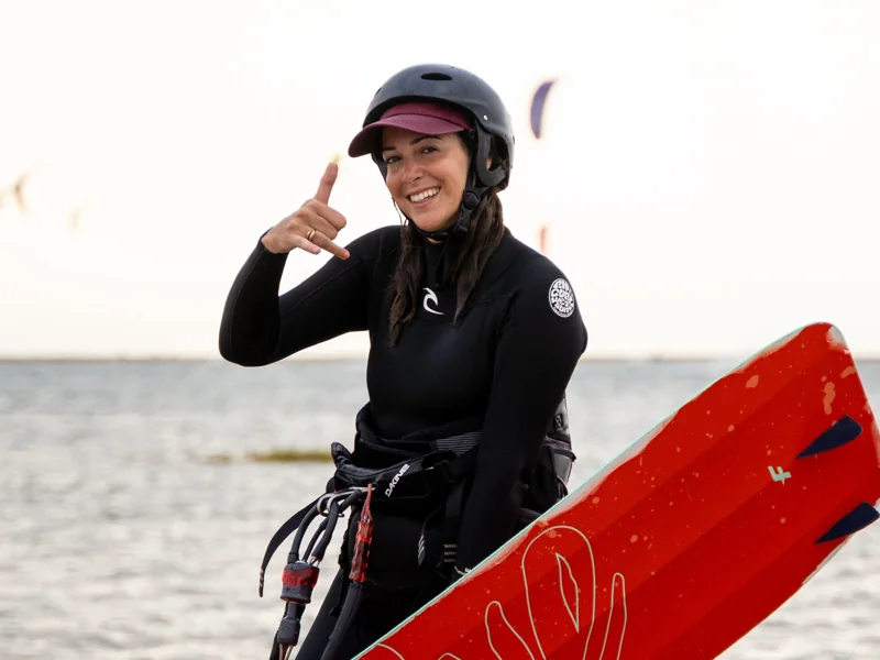 Kitesurfeuse souriante avec son casque et sa planche orange à Dakhla